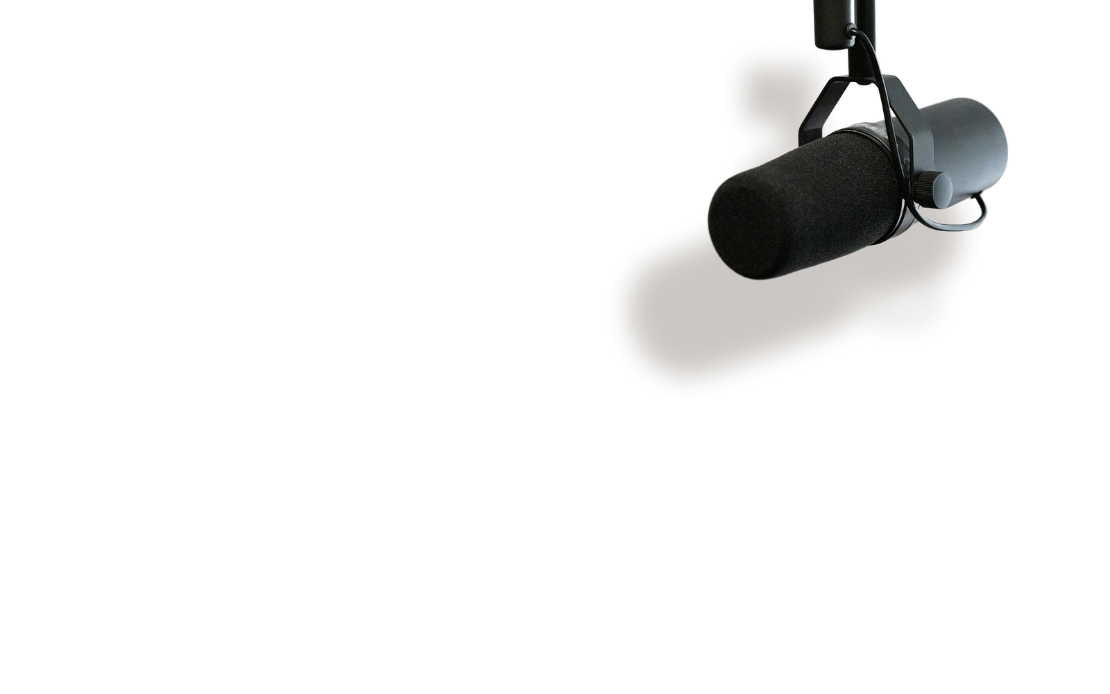 A broadcast microphone hanging from a boom arm, casting a shadow